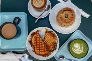 Tisch mit Bagel, Kaffe, Matcha Latte und gefüllter Waffel – ©Lilli Sprung